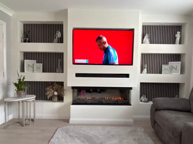 Chimney-style media wall with lit alcove shelving and electric fire